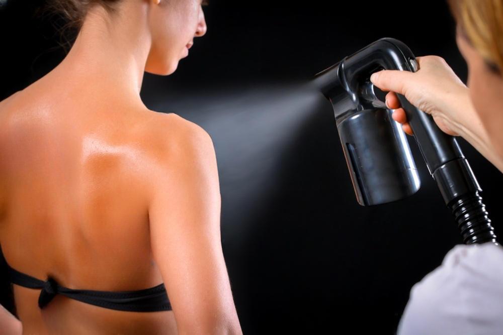 Woman receiving a spray tan treatment in a salon setting